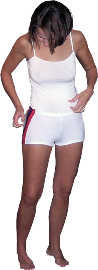 Een meisje die een witte tanktop en witte korte broek draagt, kijkt naar beneden terwijl ze haar kleding aanpast.