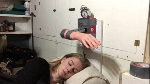 Een vrouw slaapt terwijl een mechanische arm met een nephand herhaaldelijk op haar gezicht slaat.