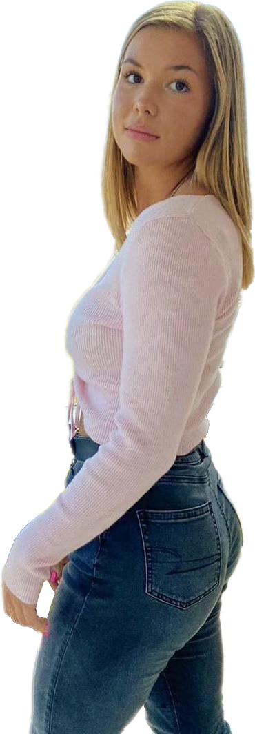 ccs21 Een vrouw met lang blond haar, gekleed in een roze shirt met lange mouwen en een donkere spijkerbroek met hoge taille, kijkt in de camera.