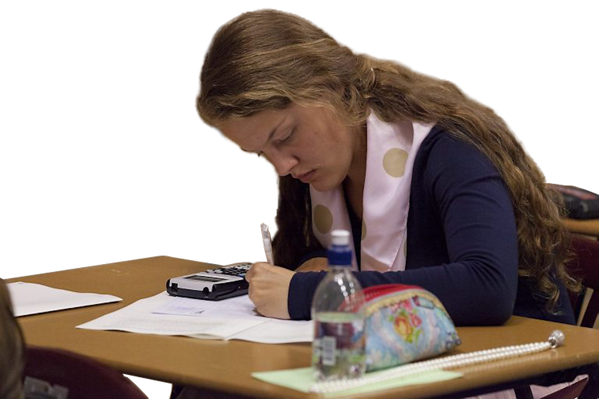 Een studente zit aan een bureau en concentreert zich op schrijven. Een rekenmachine, waterfles en etui staan op het bureau.